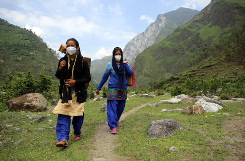 Godavari Devi, right, a community health worker, crosses the valley to provide hygiene kits and free rations to new mothers in Durmi.