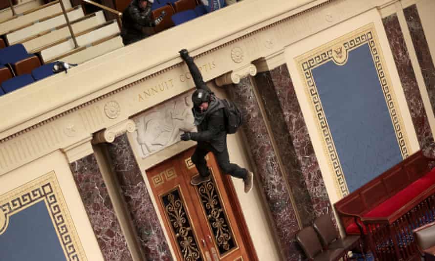 A protester is seen hanging from the balcony in the Senate Chamber.