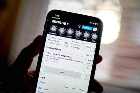A hand holds a smartphone displaying the ESPN Bet sports betting app interface