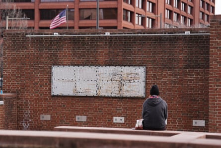 A woman sitting down in front of a wall with removed panels.