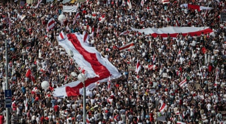 Protesters unfold giant Belarusian flags at the Minsk Hero City Obelisk