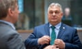 Viktor Orbán pulls his jacket together at an EU summit