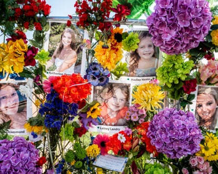 Photos of victims of the Texas floods taped to a fence among colourful flowers in Kerrville, Texas.