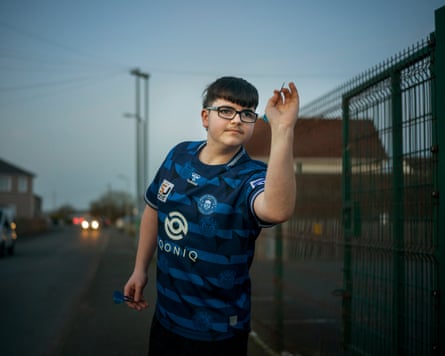 A boy holding a dart on a street, as if about to throw it