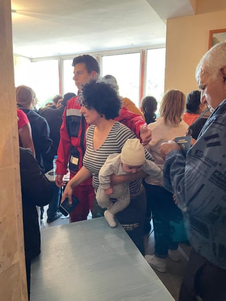 A woman holding a baby being assisted by an Armenian Red Cross volunteer in Vayk, Armenia.