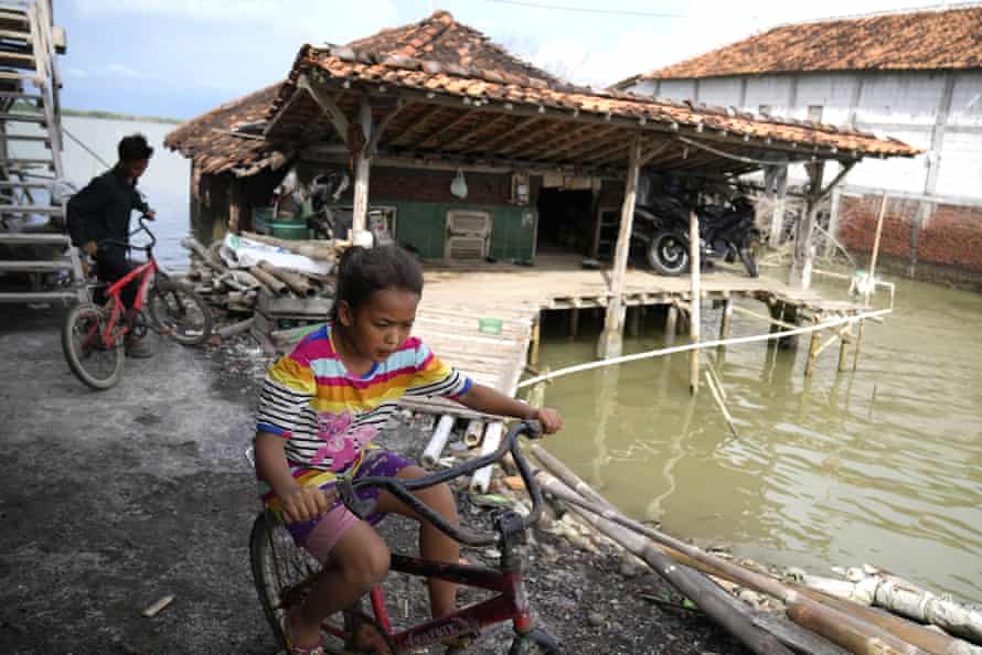 Children play near a house engulfed by sea water due to the rising sea levels in Bedono village, central Java.