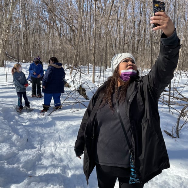 Bezhig Hunter, a fifth-grade teacher at Waadookodaading, holds her phone high so students who could not make the trip can participate virtually.