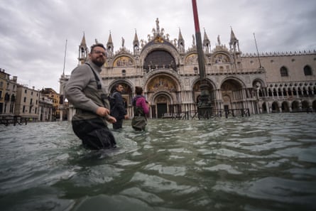 People wade through flood water in St Mark’s Square in Venice