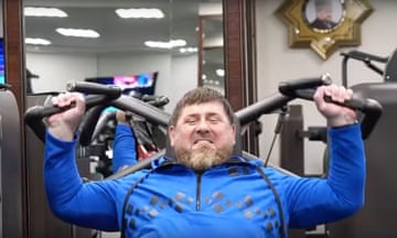 Ramzan Kadyrov using a shoulder press in a gym. His face is showing the strain from weightlifting