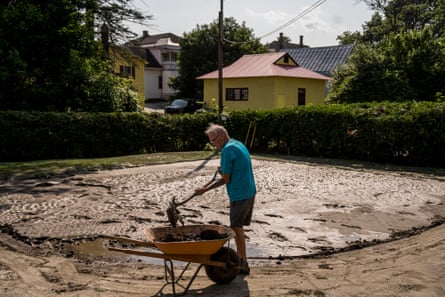 A man cleans up his backyard from mud and sediment leftover from flash flooding