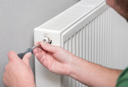 A plumber starts to bleed a radiator valve with a screwdriver