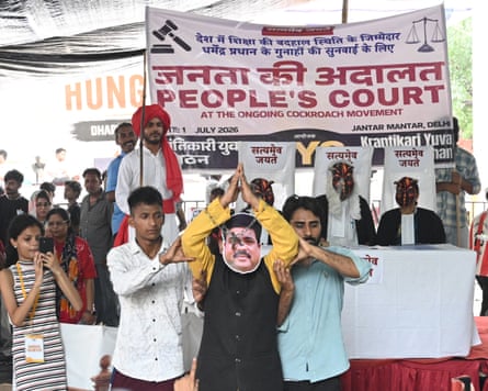 A crowd of people hold up a banner saying ‘People’s court at the ongoing cockroach movement’