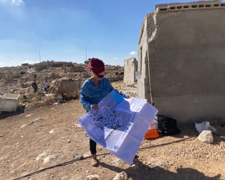 A woman standing in a deserted village looking at a map