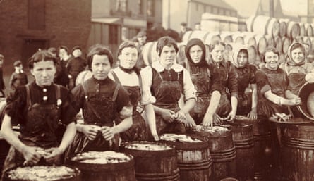 بطاقة بريدية غير مؤرخة تحتوي على صورة بني داكن لصف من النساء الاسكتلنديات يقومن بتعبئة سمك الرنجة في براميل.