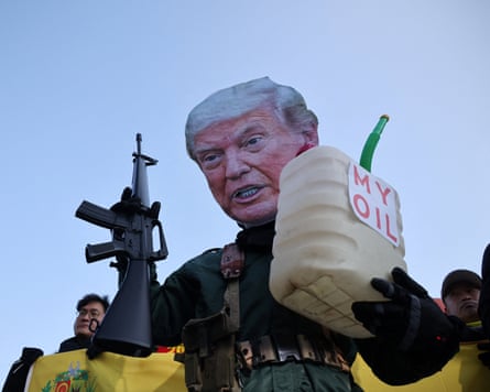 An activist, wearing a cutout mask depicting U.S. President Donald Trump, holds a toy gun and a container with the words, “My Oil” during an anti-Trump rally in South Korea.