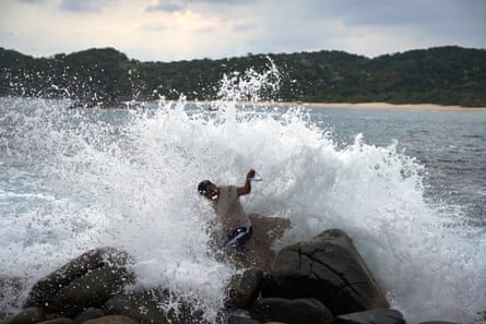 A man surrounded by sea spray as a wave hits him