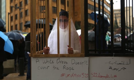 An Abaad activist dressed as a bride and wearing bandages stands in a golden cage in a protest in downtown Beirut.