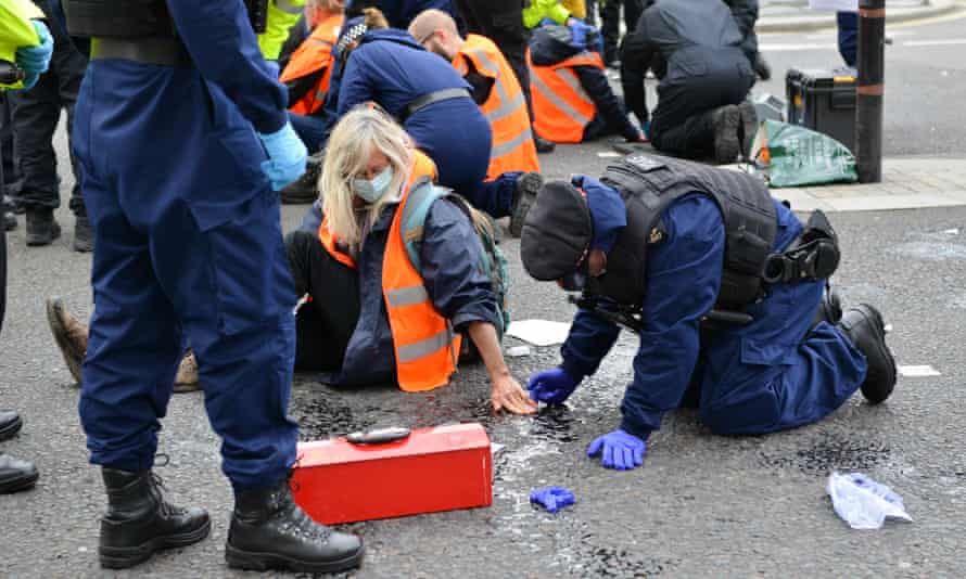 A police officer dissolves the glue on an Insulate Britain protester's hand during the demonstration outside parliament in 2021.