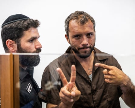 A man give the peace sign as he is escorted into court