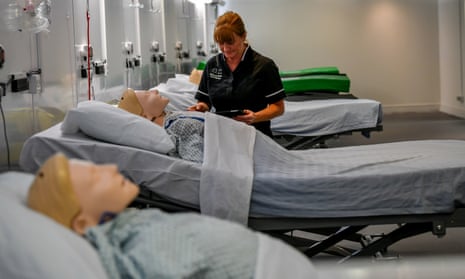 A nurse tends to a row of mannequins lying in hospital beds.
