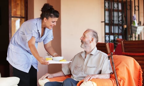 A care worker brings a meal to an older man
