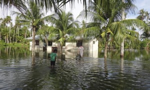 A woman and a child walk through water to reach their home during a king tide event on Kili in the Marshall Islands
