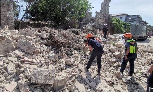 Rescuers and a policeman inspect a collapsed structure in Ilocos Sur province.