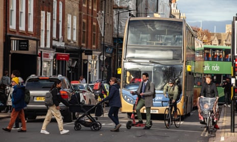 Cyclists, pedestrians, buses and cars in busy high street.
