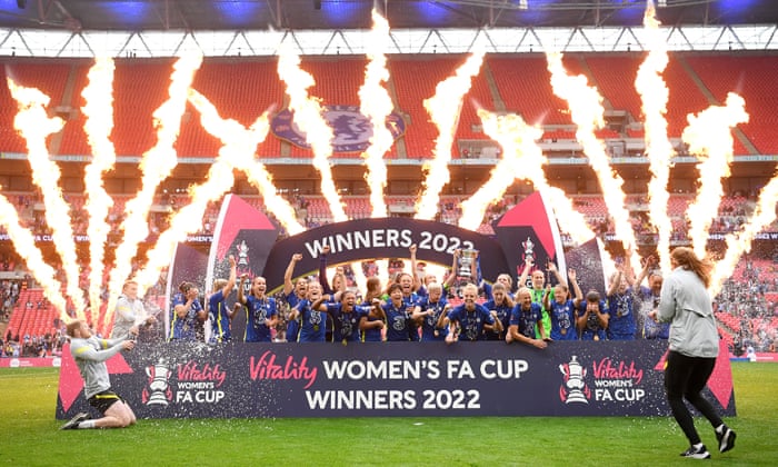 Magdalena Eriksson and Millie Bright of Chelsea lift the Women’s FA Cup trophy as their team-mates celebrate in front of pyrotechnics.