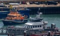 An RNLI lifeboat docking next to a Border Force vessel in a harbour