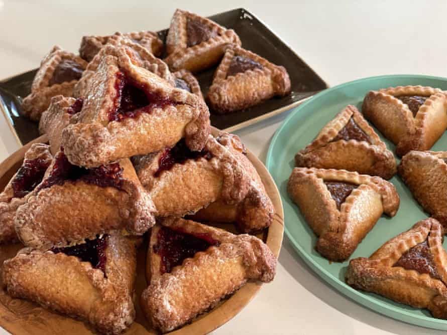 Three plates hold hamantaschen, a triangular cookie that resembles a hat with a fruit filling.