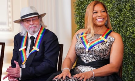 Barry Gibb and Queen Latifah sitting on chairs