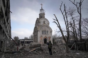 A soldier takes a photograph of a damaged church after shelling in a residential district of Mariupol.
