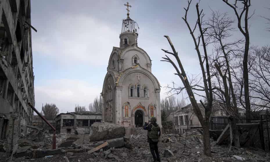 A Ukrainian serviceman takes a photograph of a damaged church after shelling in a residential district in Mariupol, Ukraine.