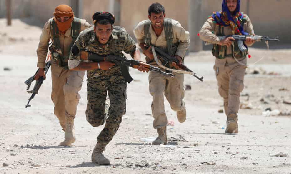 Kurdish fighters run across a street in Raqqa, Syria on July 3, 2017