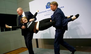 Security officers detain protester Jo Witt who jumped on the table in front of the European Central Bank President Mario Draghi during a news conference in Frankfurt, April 15, 2015.