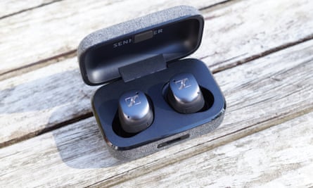 The earbuds shown clipped into their case with the lid open on a table