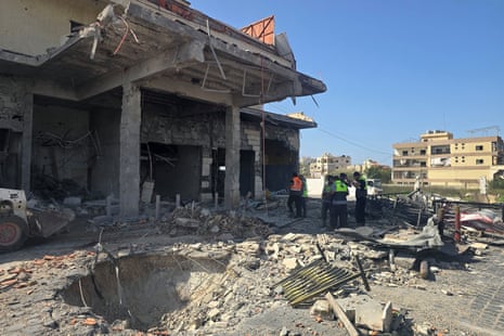 आपातकालीन कर्मचारी मलबे और क्षतिग्रस्त इमारत के पास खड़े हैं।