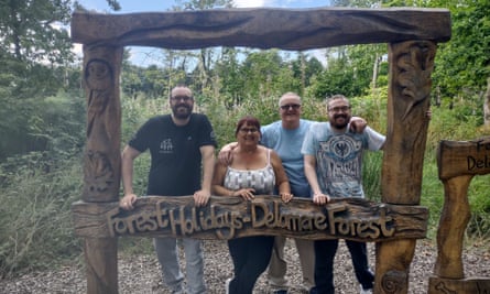 Janet Williams, with her husband and sons, standing in a wooden frame that says "Forest Holidays Delamere Forest: