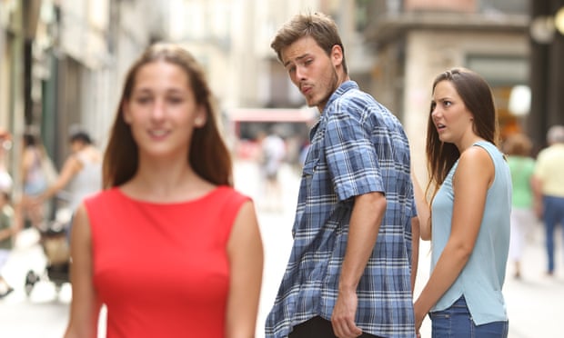 Man walking with girlfriend and looking over shoulder at another woman
