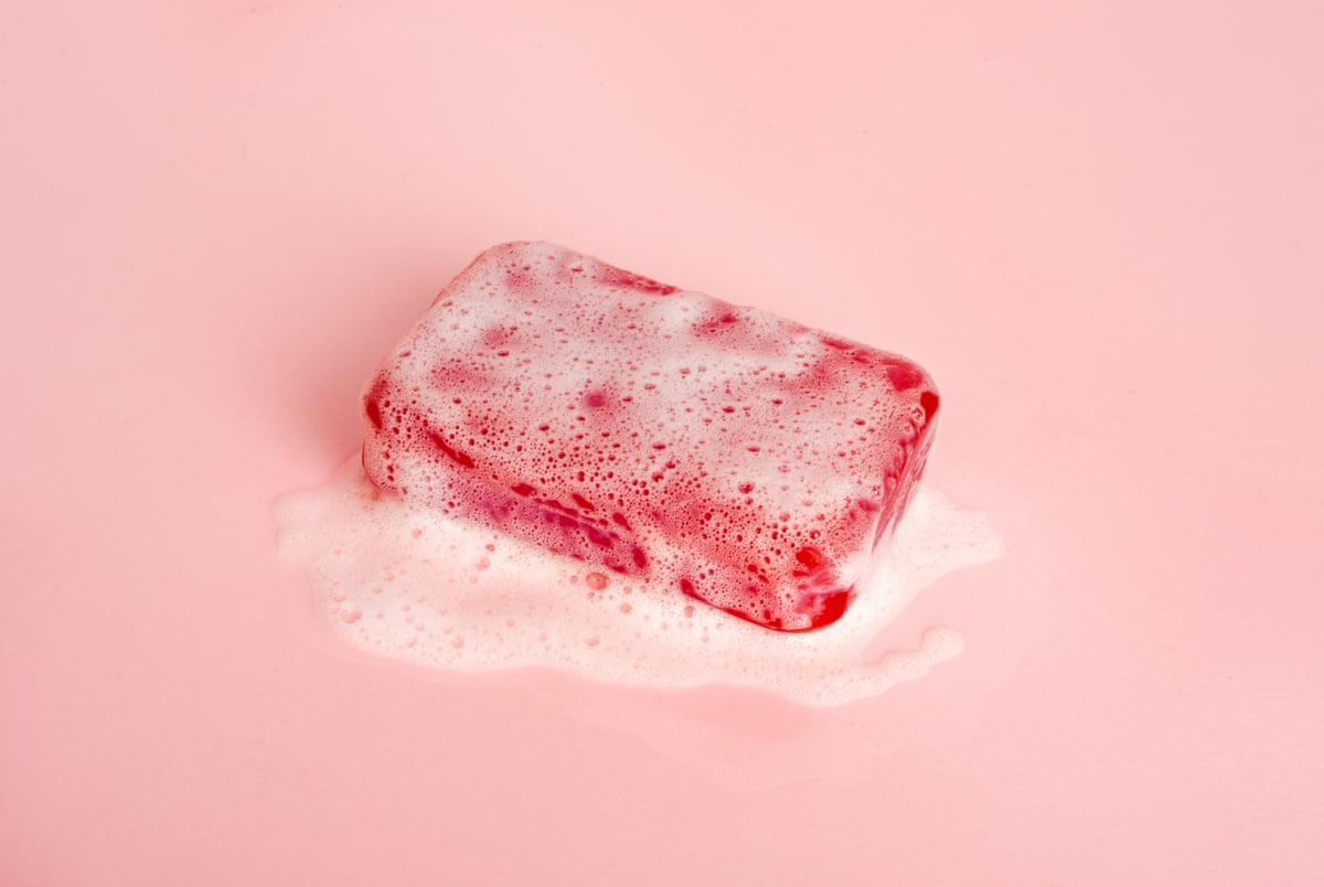 A red bar of soap with a lathered layer of bubbles.