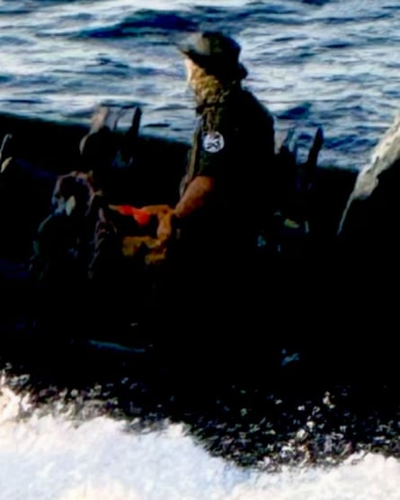 Low resolution pic of a man on a boat facing away from camera with his armband showing