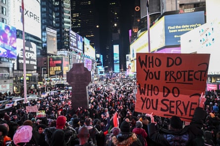 People gather in Times Square in New York to protest the death of Tyre Nichols at the hands of police. A large sign at right reads ‘Who do you protect? Who do you serve?’