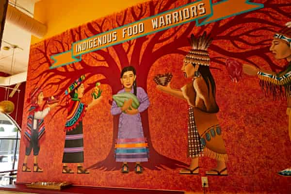 A mural with a bright orange-red background shows a woman standing under a tree.  The other four people stand next to him and offer food.