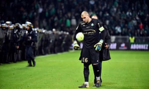 Stéphane Ruffier trudges off the pitch as police keep the home fans at bay.