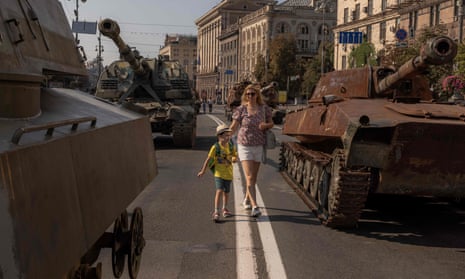 A woman and a young boy look at destroyed Russian armored military vehicles on display in Kyiv.
