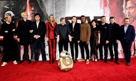 A bunch of people standing on a red carpet. And a small robot