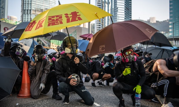 Protesters with umbrellas crouch in the street
