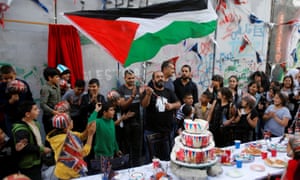 Man holds a Palestinian flag as people take part in an event ahead of the anniversary of the Balfour Declaration, outside Banksy’s Walled Off Hotel in the West Bank city of Bethlehem