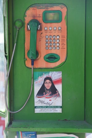 A green and orange public phone with a campaign sticker.